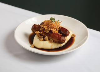 sausages on a plate sitting on top a mound of mash