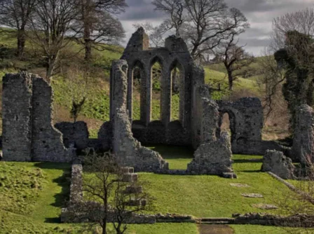 Ancient stone ruins surrounded by lush greenery and rolling hills in a tranquil setting.