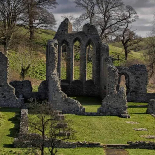 Ancient stone ruins surrounded by lush greenery and rolling hills in a tranquil setting.