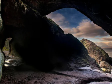 Family exploring a scenic seaside cave with views of a stunning coastline.