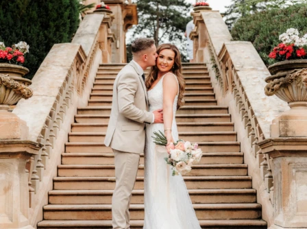 Couple smiling on elegant stone staircase at Hastings Hotels garden.