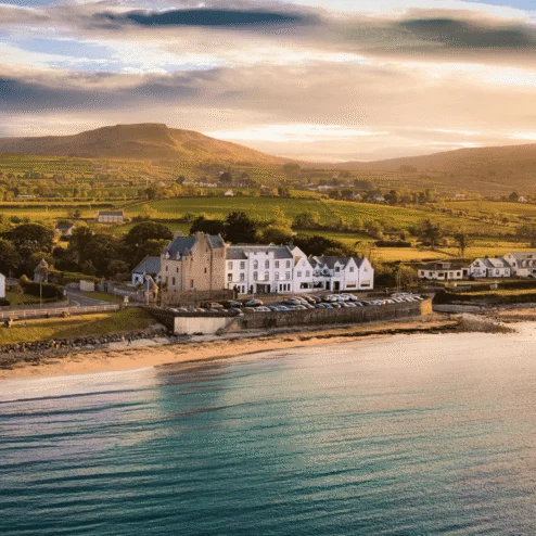 A picturesque coastal hotel near rolling hills at sunset, inviting for family retreats.