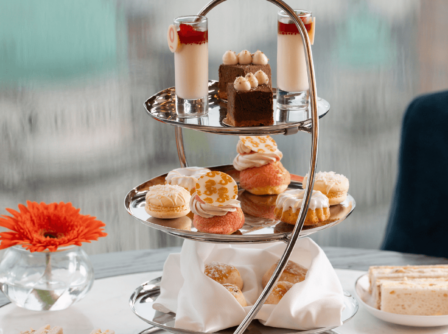 Elegant afternoon tea with pastries and sandwiches on a table in a cosy hotel setting.