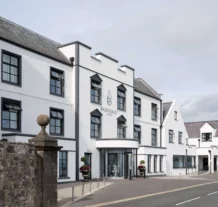Elegant white hotel exterior with flowers, inviting entrance, and clear road view.