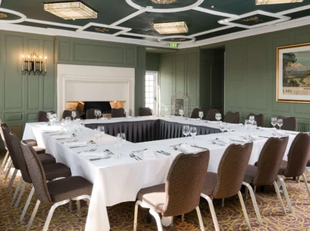Elegant hotel meeting room with a U-shaped table set for a gathering.