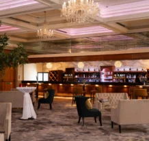 Elegant hotel lounge with plush seating and a well-stocked bar under a sparkling chandelier.