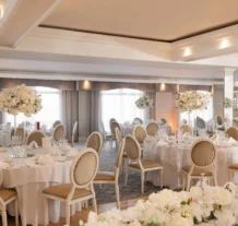 Elegant hotel dining room set for a wedding reception with white floral centrepieces.