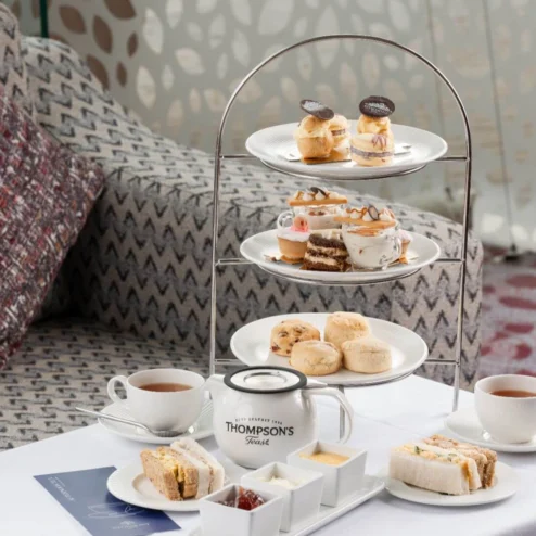 Afternoon tea setup with sandwiches, scones, and pastries in a cosy hotel lounge.