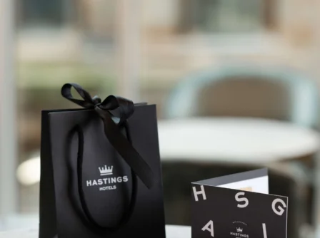 Elegant Hastings Hotels gift bag and card on a sunlit table.