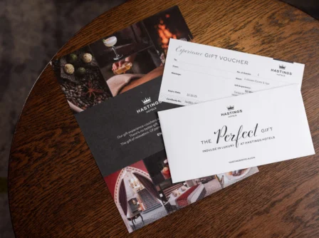 Hastings Hotels gift vouchers on a wooden table, offering luxurious experiences.