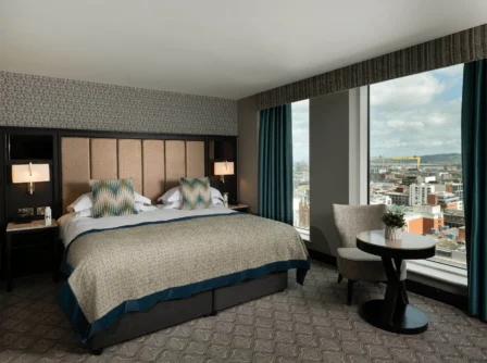 Luxurious hotel room with king bed and city view, inviting relaxation and comfort.