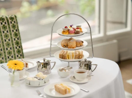 Elegant afternoon tea setup with pastries and scones in a charming hotel setting.