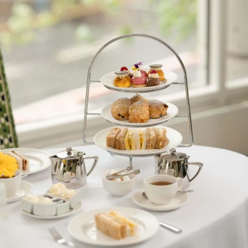 Elegant afternoon tea setup with pastries and scones in a charming hotel setting.
