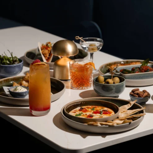 An inviting table set with cocktails and gourmet dishes at Hastings Hotels.