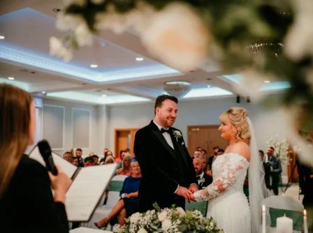 A couple exchanges vows at a beautifully decorated indoor wedding ceremony.