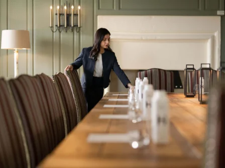 Hotel staff preparing an elegant dining table in a cosy, warmly-lit room.