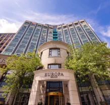 Exterior of Europa hotel with green trees and clear blue sky.