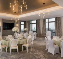Elegant hotel dining room set for a banquet with floral centrepieces and soft lighting.