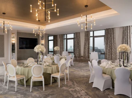 Elegant hotel dining room set for a banquet with floral centrepieces and soft lighting.