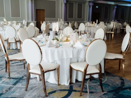 Elegant dining tables set for an event in a luxurious hotel banquet hall.