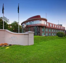 Modern hotel exterior with green lawn at sunset.