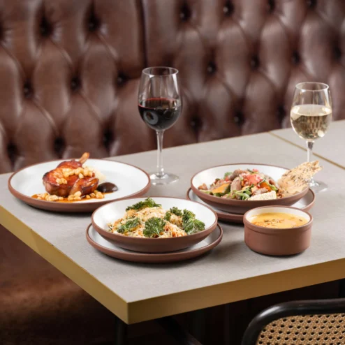 Elegant table setting with gourmet dishes and wine in a cosy, upscale restaurant.