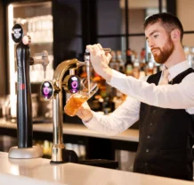 Friendly bartender pouring a draft beer in a hotel bar, surrounded by elegant decor.