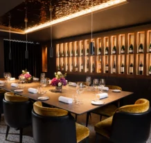 Elegant dining room with a large table, wine display, and floral centrepiece at Hastings Hotels.