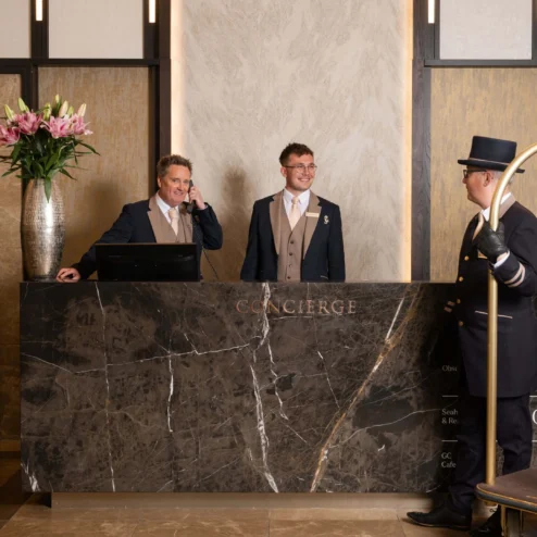 Welcoming concierge staff assisting guests at luxury hotel reception.