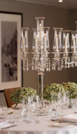 Elegant dining table set with crystal candelabras and lush greenery centrepieces.