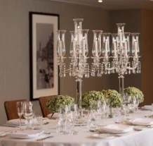 Elegant dining table set with crystal candelabras and lush greenery centrepieces.