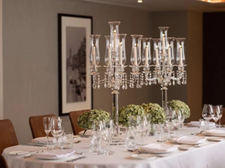 Elegant dining table set with crystal candelabras and lush greenery centrepieces.
