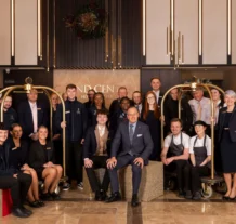 Friendly hotel staff group in a warmly lit lobby with elegant decor.