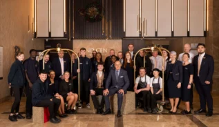Friendly hotel staff group in a warmly lit lobby with elegant decor.
