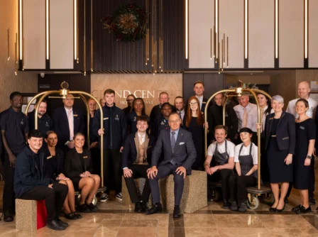 Friendly hotel staff group in a warmly lit lobby with elegant decor.