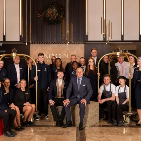Friendly hotel staff group in a warmly lit lobby with elegant decor.