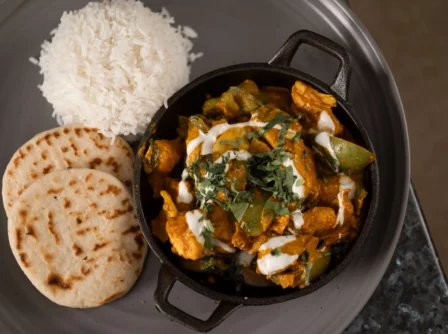 Aromatic curry and rice with naan on a plate, offering a warm dining experience.