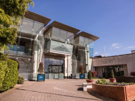 Modern hotel entrance with inviting glass facades and lush greenery.