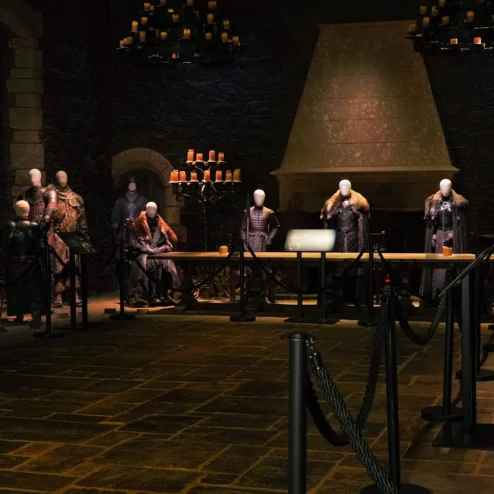 Guests exploring historical armour display in elegant, dimly-lit hotel hall.
