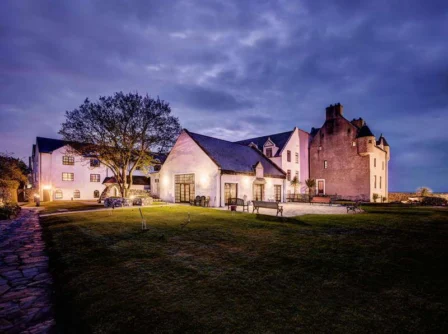 A cosy evening view of a historic Hastings Hotel with warm lights illuminating the garden.