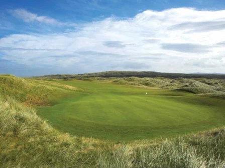 Family enjoying a stroll on a lush green golf course with rolling hills under a blue sky.