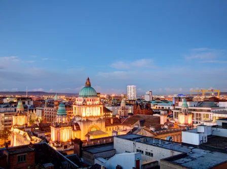 Aerial view of an illuminated cityscape with historic domed buildings at dusk.
