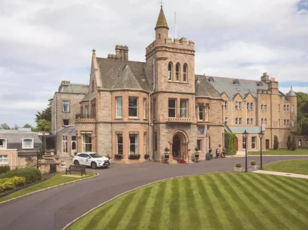 A family arrives at a grand hotel with manicured lawns and historic architecture.