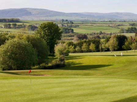 Family enjoying a day at a scenic golf course with lush greenery and rolling hills.