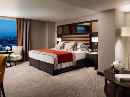 Spacious hotel room with sea view, double bed, cosy chairs, and elegant decor.