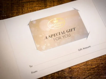 Hastings Hotels gift voucher on wooden table, ready for a personalised message.