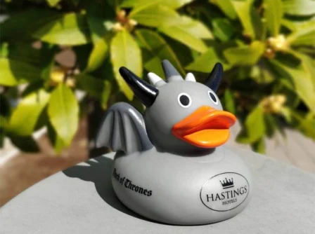 Grey dragon duck ornament with "Hastings Hotels" logo, outdoors on a sunny day.