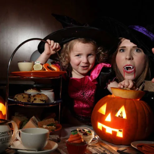 Family enjoying Halloween afternoon tea with pumpkin decorations at Hastings Hotels.
