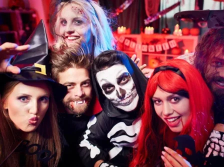 Family in Halloween costumes celebrating in a festive, decorated room.