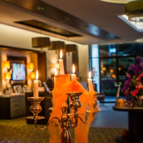 A warmly lit hotel lobby with festive autumn decor and elegant candlelight.